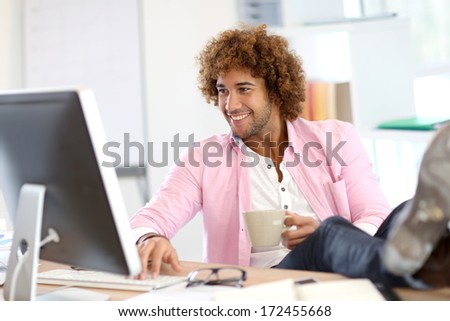 Young smiling man in office with feet on desk