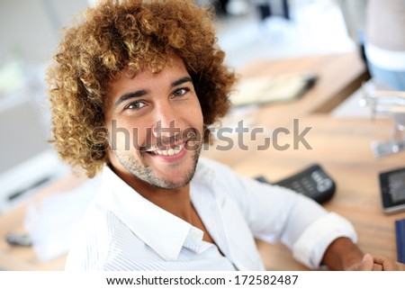 Handsome smiling businessman in front of desktop