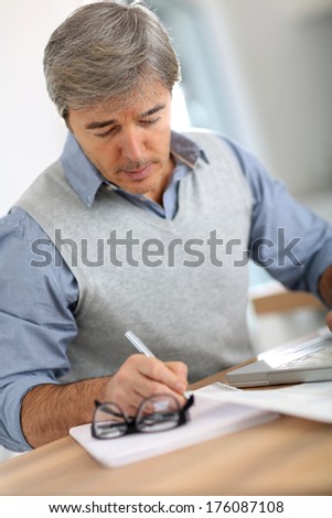 Senior man in office writing on paper