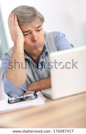 Businessman with worried expression while reading email