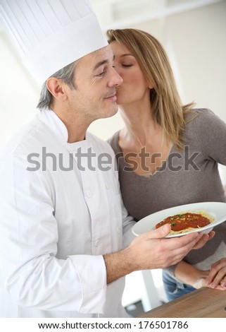 Chef preparing pasta dish for woman