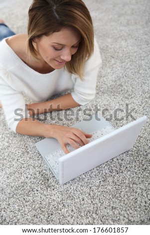 Upper view of woman using laptop laying on carpet