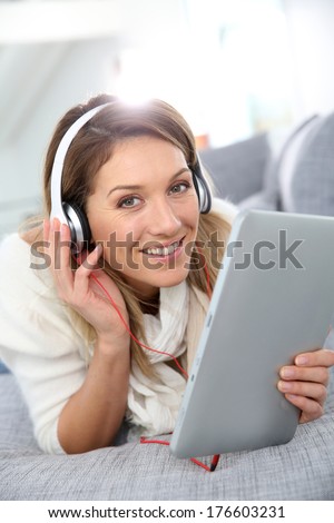 Smiling woman listening to music with tablet and headphones