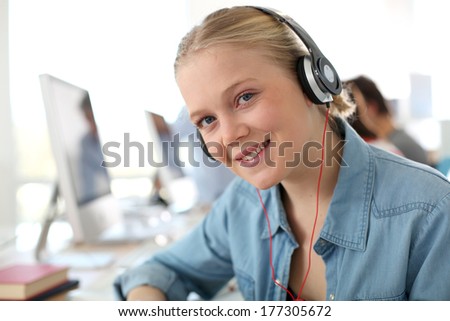 Blond student girl in computing class with headphones on