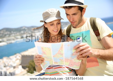 Cheerful young couple of travelers reading city map
