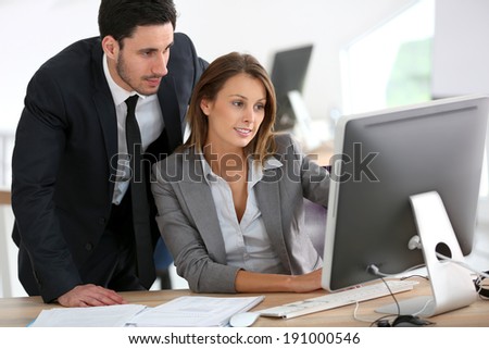 Manager with businesswoman working on desktop