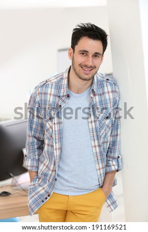 Smiling man leaning on wall in office
