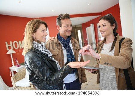Real estate agent giving house keys to clients