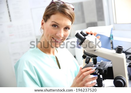 Doctor in laboratory looking through microscope