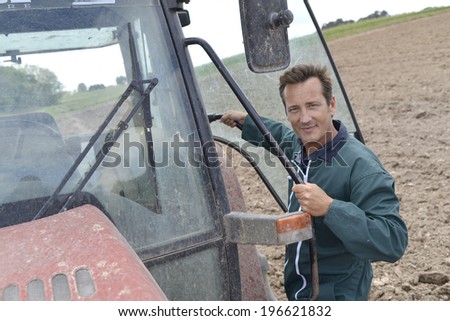 Farmer climbing into tractor out in farming land
