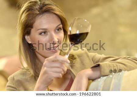 Woman tasting red wine in cellar