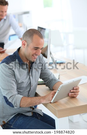 Young smiling man in training class using digital tablet