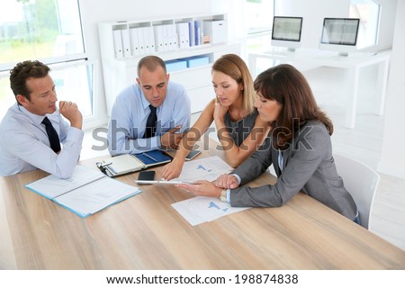 Group of business people meeting around table with tablet
