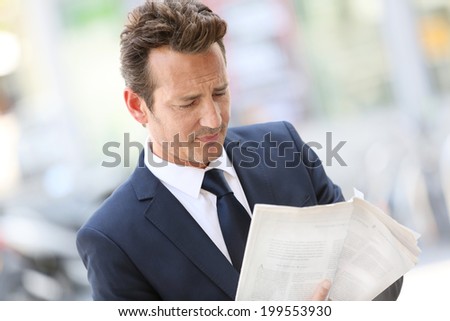 Handsome businessman in town holding newspaper
