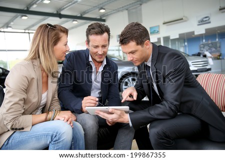 Couple signing car purchase order on digital tablet