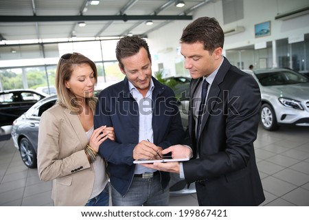 Couple signing car purchase order on digital tablet