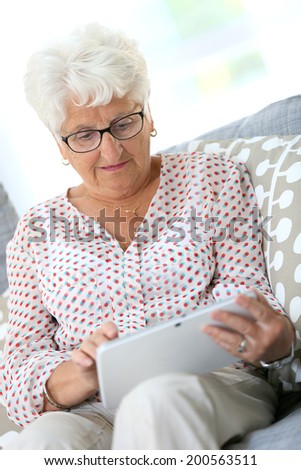 Elderly woman using digital tablet at home