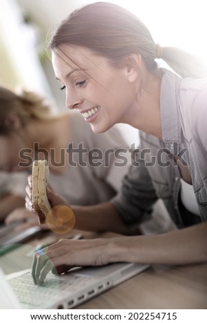 Business girl eating sandwich in front of laptop