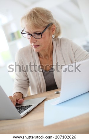 Senior woman filling form online with laptop
