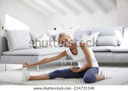 Young woman at home stretching out after exercising