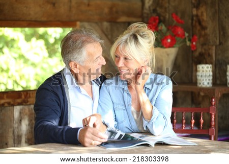 Senior couple in yard reading magazine