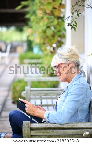 Senior woman reading book sit on bench