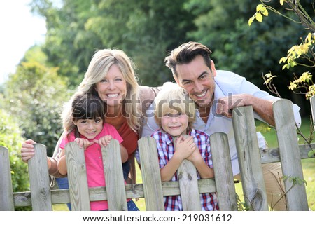 Happy family leaning on fence by country home