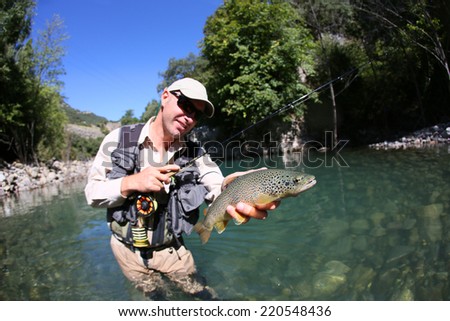 Fly fisherman holding fario trout recently caught