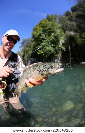 Fly fisherman holding fario trout recently caught