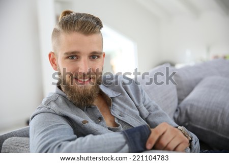 Portrait of trendy guy with beard relaxing at home