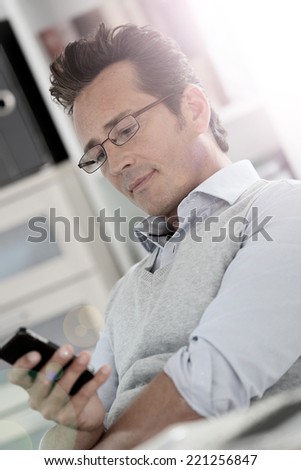 Relaxed businessman in office using smartphone