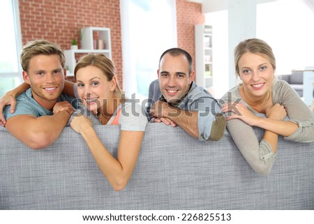 Cheerful roommates sitting in sofa at home