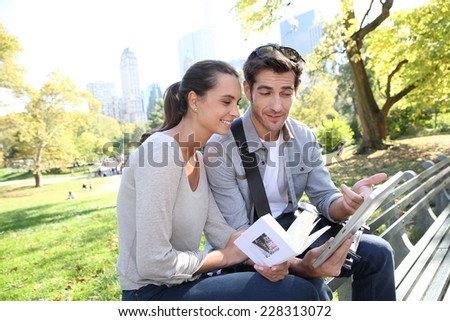 Couple of tourists looking at traveler\'s guide in Central Park