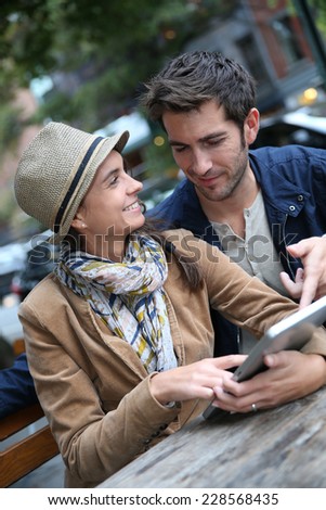 Couple in town sitting in coffee shop and using digital tablet