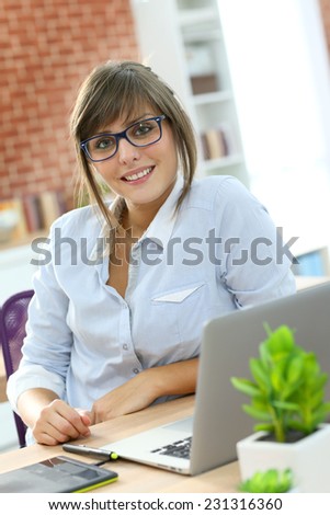 Creative young woman working in office with graphic tablet
