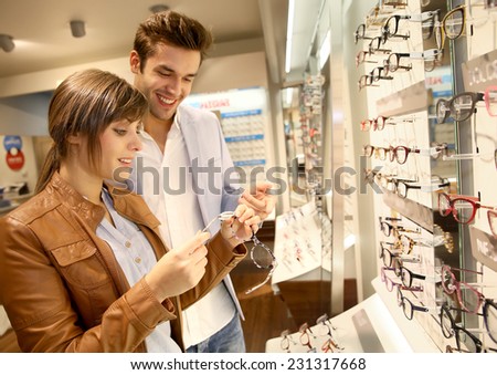 Young couple in optical shop trying eyeglasses