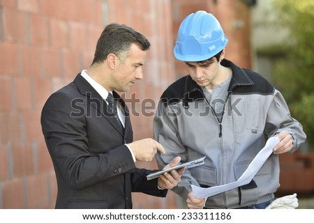 Contractor on building site checking different points with worker