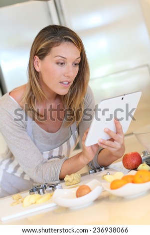 Smiling blond woman looking at recipe on digital tablet