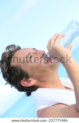 Handsome man drinking water from bottle after exercising