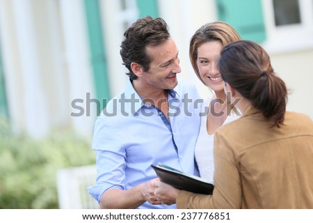 Couple meeting real-estate agent outside new property