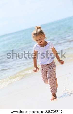 Cheerful 4-year-old girl running on a sandy beach