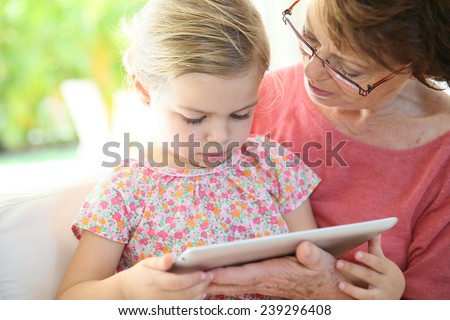 4-year-old girl with grandma playing on digital tablet