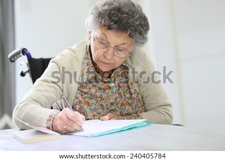 Elderly woman in wheelchair filling up medical form