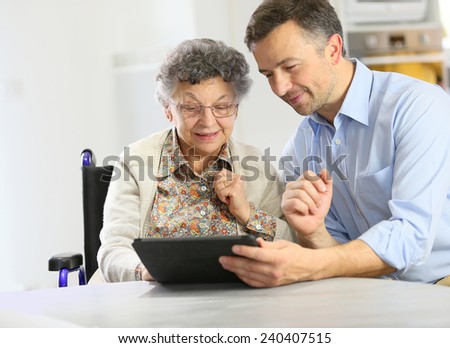 Man with elderly woman using digital tablet