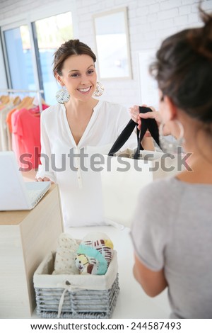 Seller woman in store giving purchase bag to client