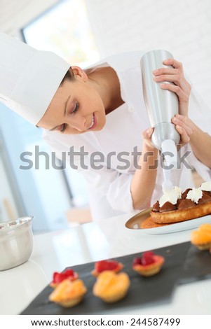 Pastry cook spreading whipped cream on tart