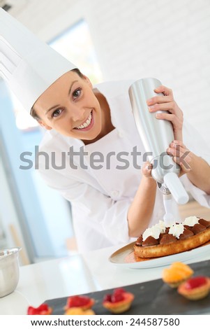 Pastry cook spreading whipped cream on tart