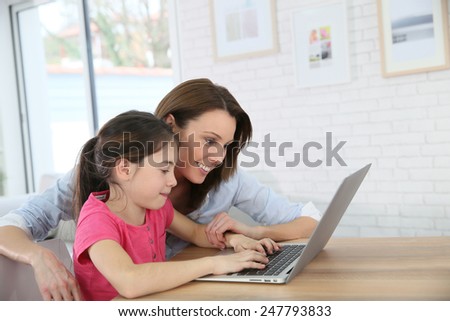 Mother and daughter playing on laptop computer