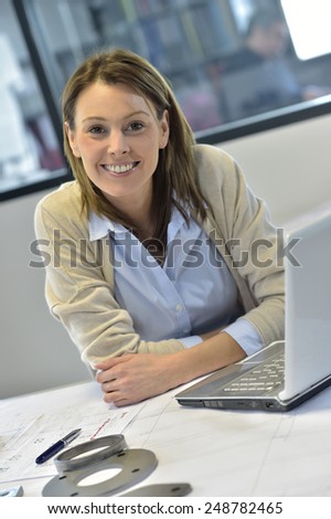 Smiling woman in office working on laptop