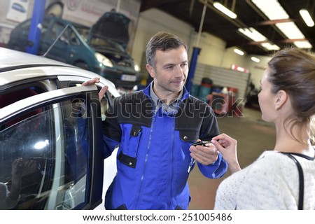 Auto repair mechanic giving car keys back to customer